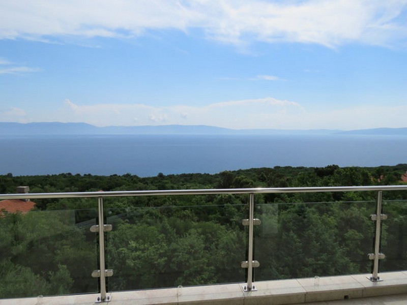 Parapetto in vetro con vista sul bosco, sul mare e sull'isola