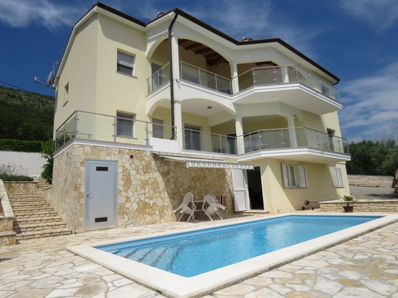 Villa gialla con tre livelli di balconi e piscina davanti
