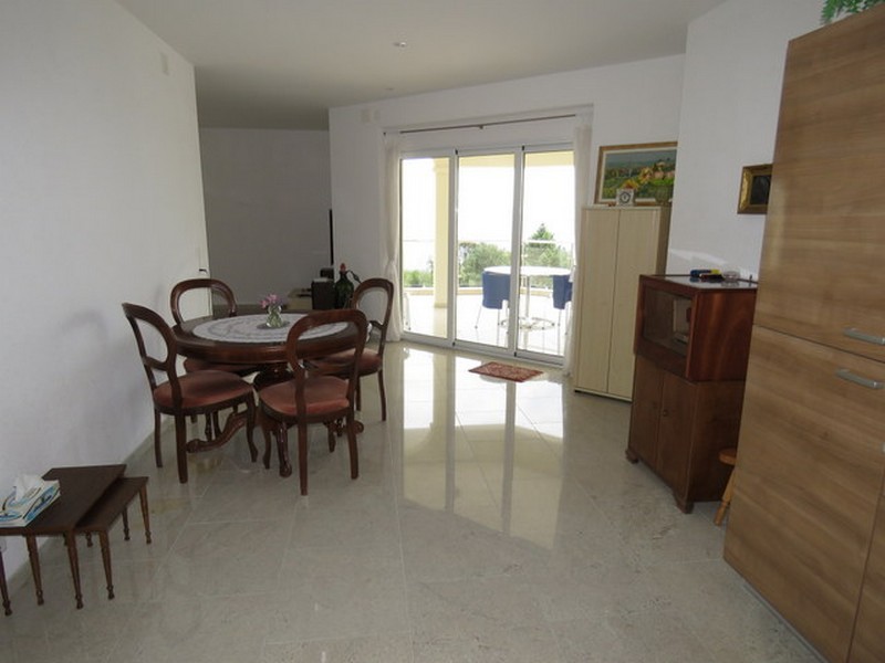 Zona pranzo con tavolo rotondo e accesso alla terrazza con vista mare.