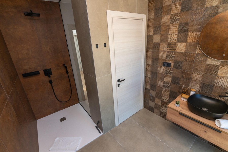 Bagno moderno con doccia aperta ed eleganti piastrelle