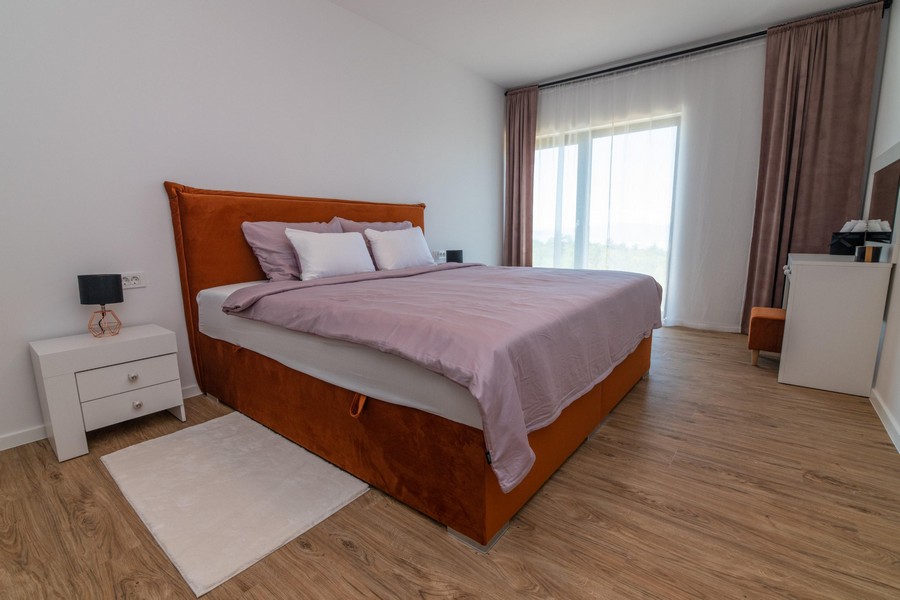 Camera da letto con letto arancione e grandi finestre