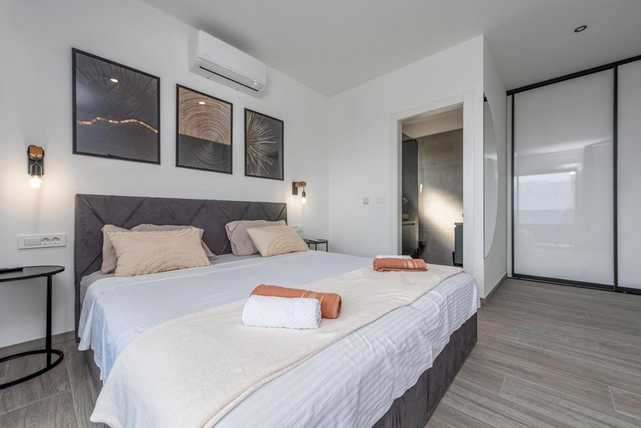 Camera da letto con letto grande, quadri moderni e accesso diretto al bagno.
