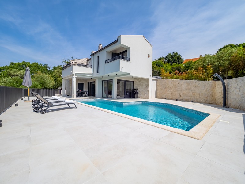 Piscina con lettini davanti alla casa lungo il muro in pietra naturale