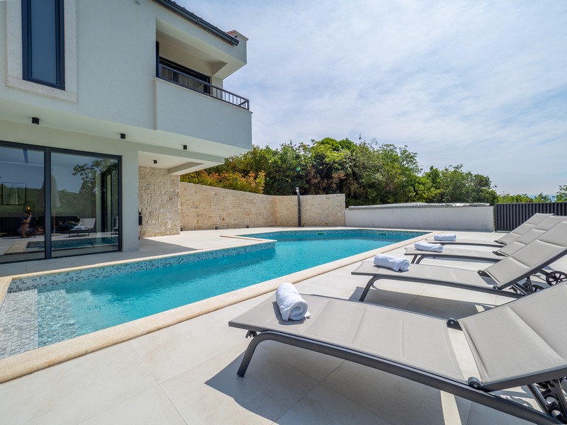 Villa con piscina e sedie a sdraio all'esterno