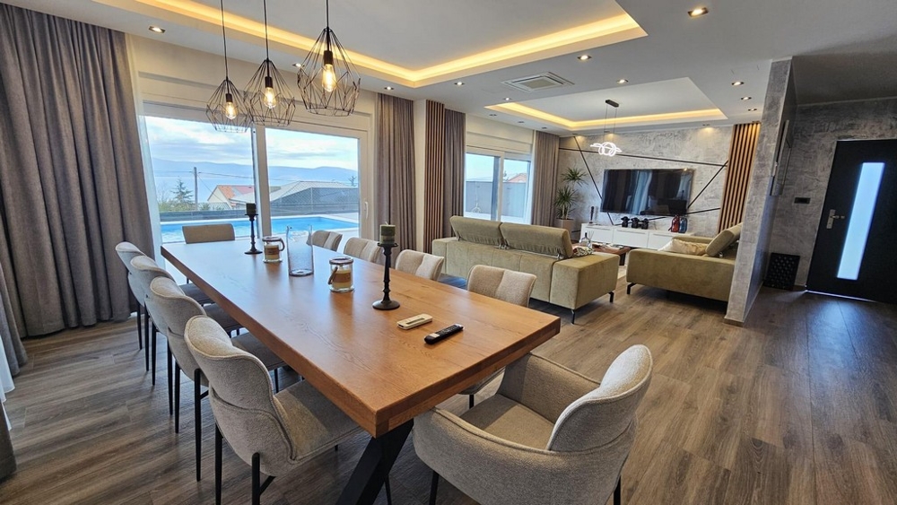 Soggiorno moderno con zona pranzo e vista sulla terrazza e sulla piscina