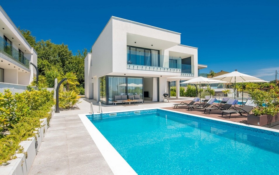 Villa bianca con piscina e ombrelloni nel giardino di ghiaia