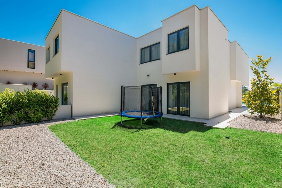 Giardino moderno con casa bifamiliare e trampolino