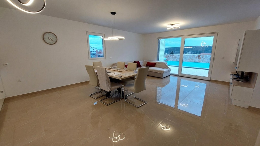Zona giorno aperta con tavolo da pranzo e vista sulla piscina, immobile H3491