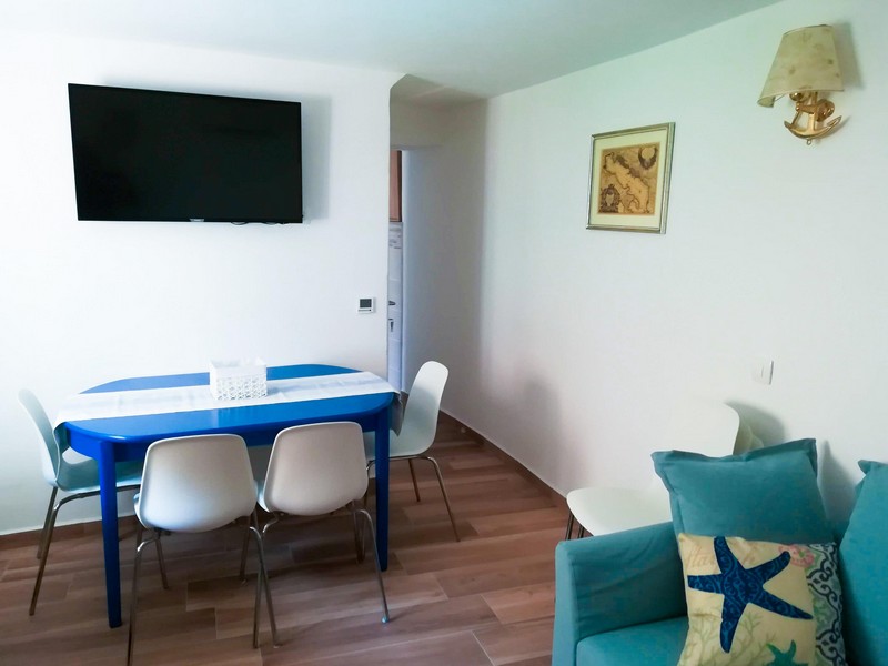 Zona pranzo con TV e tavolo blu