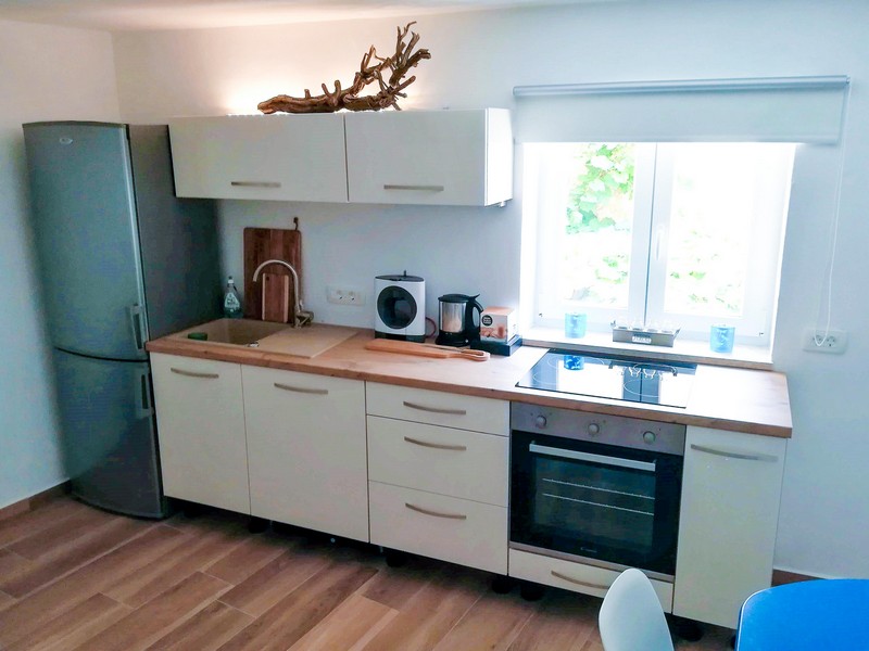 Cucina luminosa con piano in legno e dotazioni moderne
