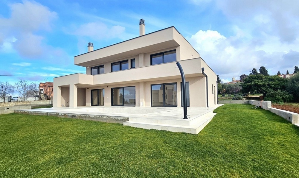 Nuova costruzione beige con terrazza e prato fresco