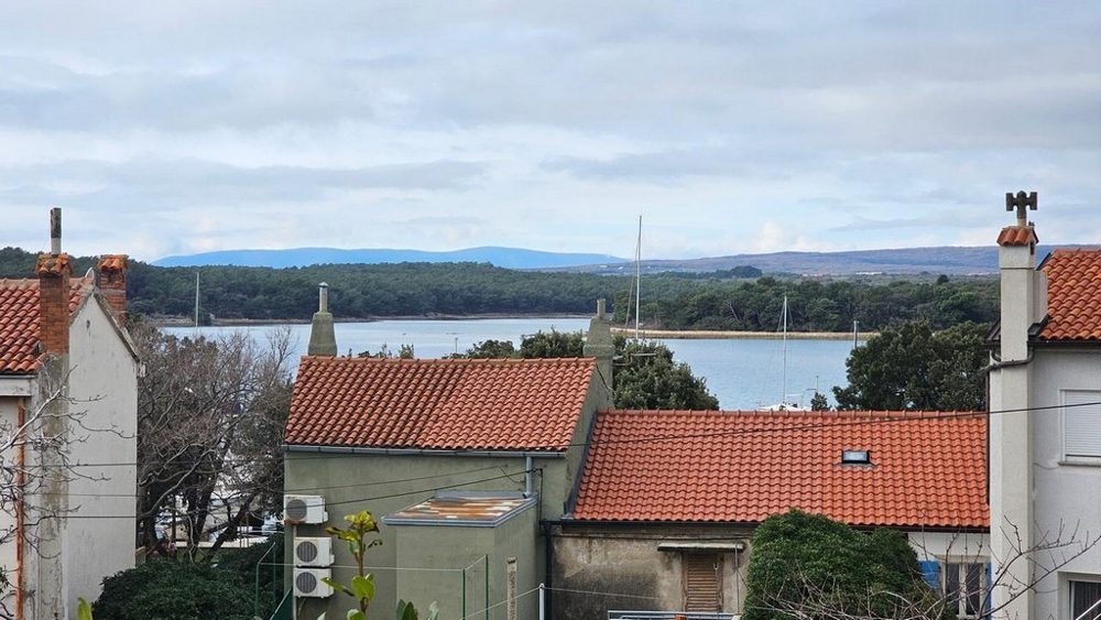 Tetti di tegole con vista sulla baia fino al bosco