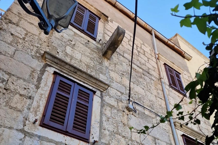 Facciata della casa in pietra con persiane e pareti in pietra naturale