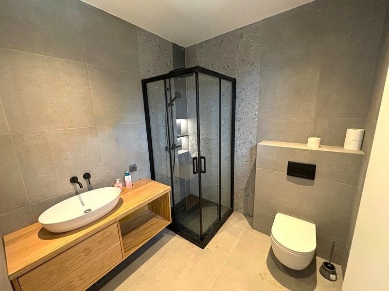 Bagno moderno con doccia in vetro e lavabo in legno
