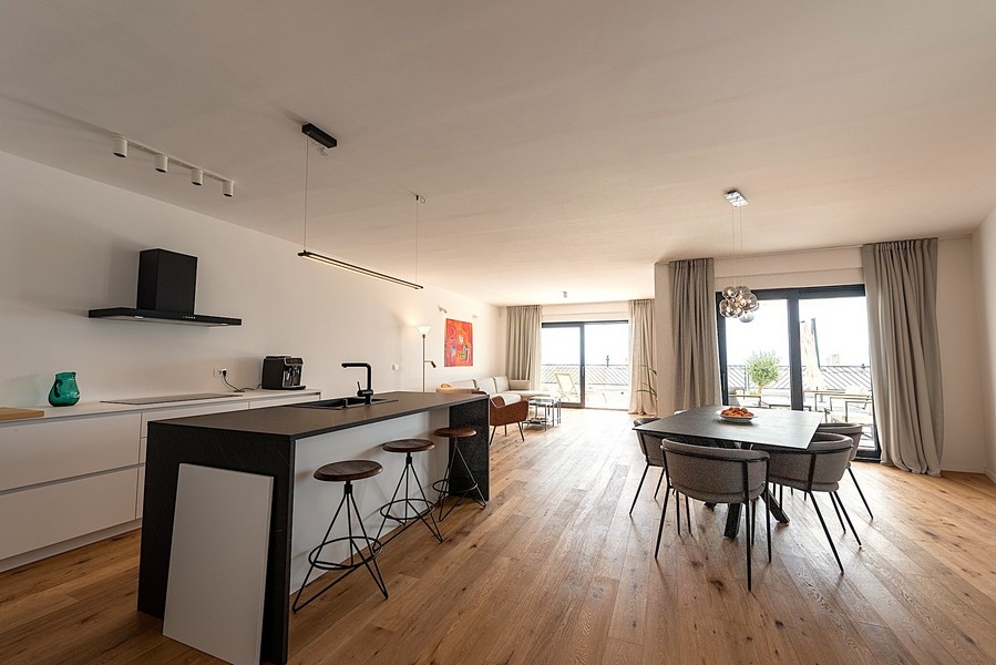 Cucina moderna con isola, zona pranzo e zona giorno sullo sfondo