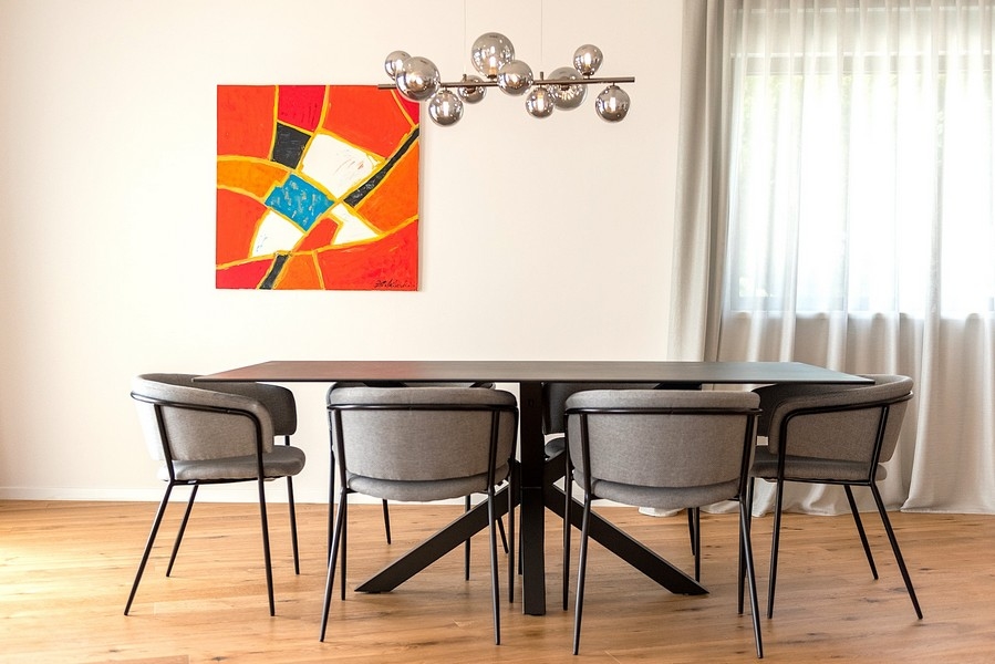 Zona pranzo con lampada di design e grande opera d'arte alla parete