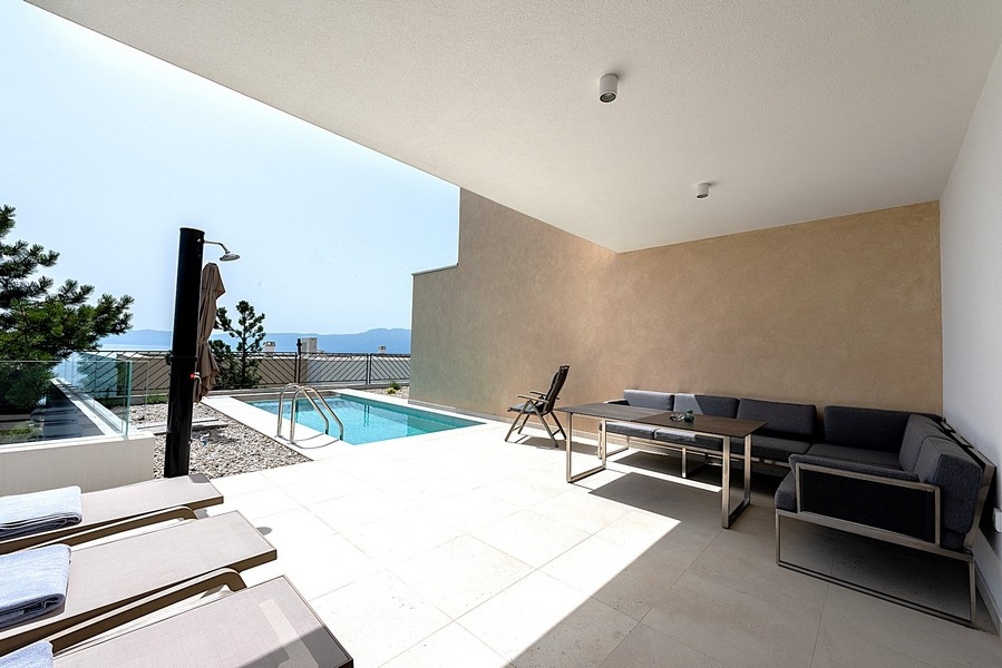 Terrazza con piscina, sedie a sdraio e vista mare