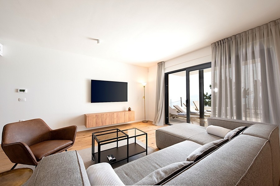 Soggiorno con divano grigio, TV e accesso alla terrazza