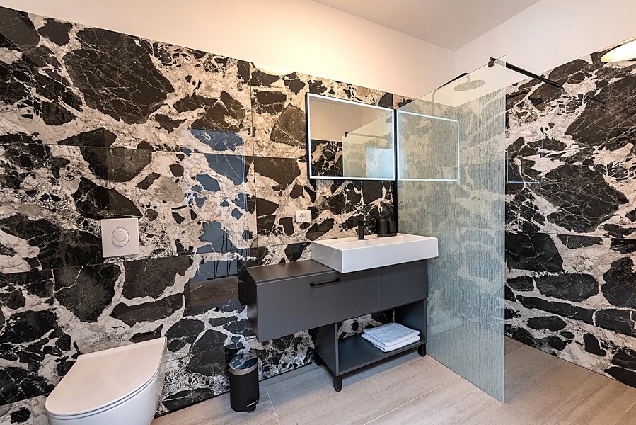 Bagno moderno con parete in marmo nero e doccia a filo pavimento