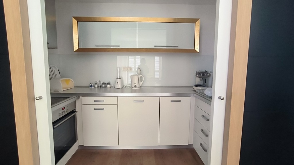 Cucina compatta con mobili da incasso bianchi e accenti dorati