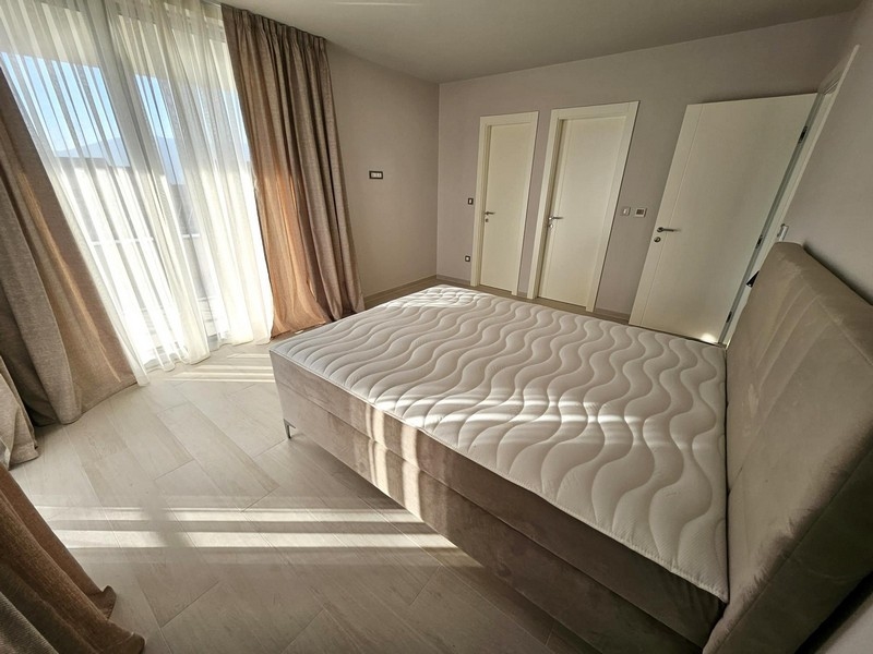 Ampia camera da letto con grandi finestre e letto matrimoniale
