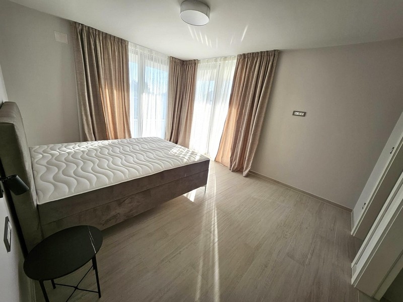 Camera da letto luminosa con letto matrimoniale, tende e porte del balcone