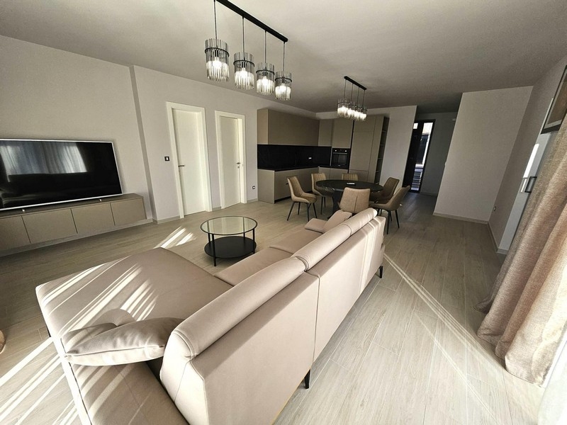 Zona giorno aperta con divano, TV e lampade di design