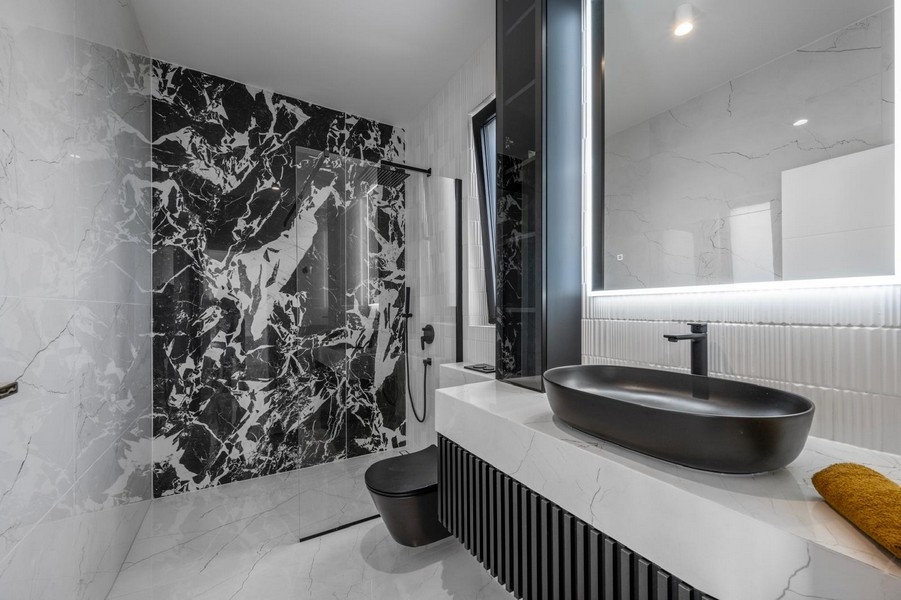 Elegante bagno con piastrelle in marmo e dotazioni nere