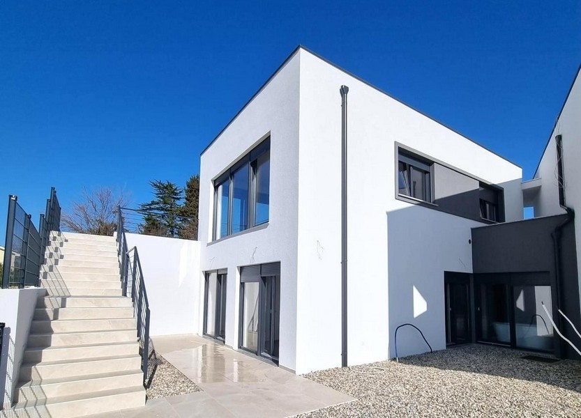 Edificio nuovo bianco con scala esterna e aiuola di ghiaia