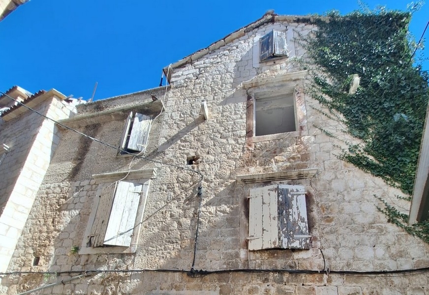 Vecchia casa in pietra con persiane consumate ed edera