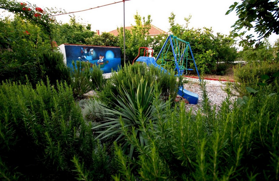 Parco giochi per bambini in giardino con molto verde