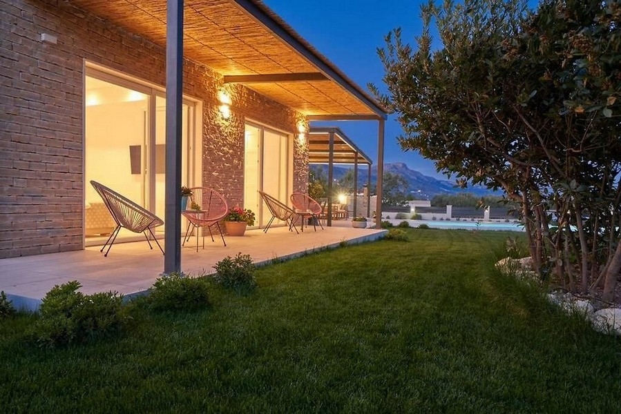 Veranda illuminata con poltrone in rattan e piscina nella luce della sera