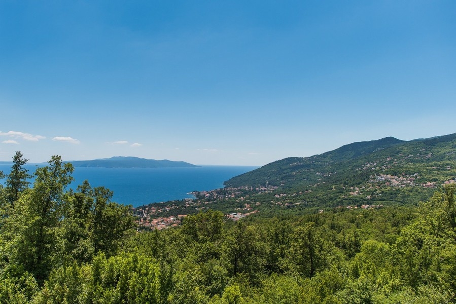 Vista sopra il bosco e il paese costiero fino al mare e all'isola