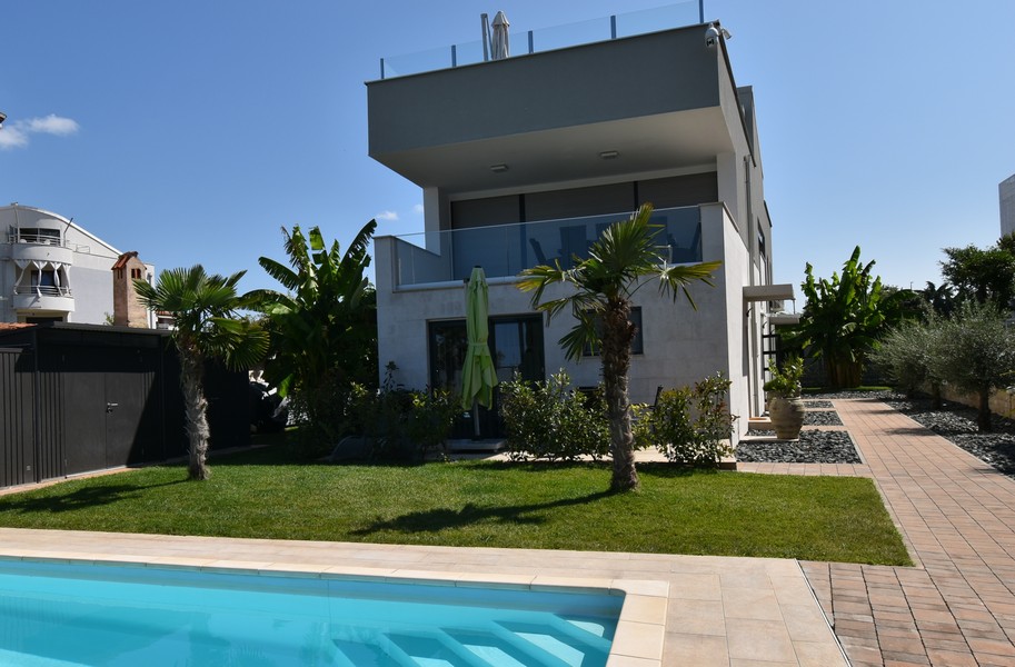 Villa moderna con palme e piscina nell'erba sintetica