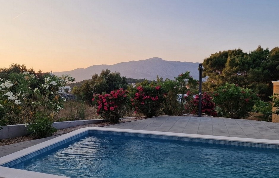 Piscina con oleandri in fiore davanti alla catena montuosa