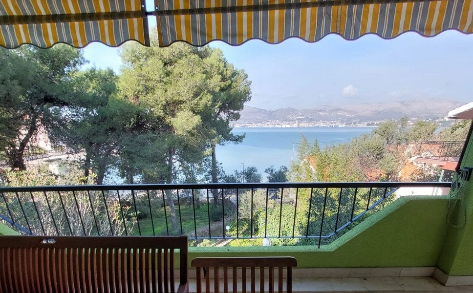 Balcone sotto la tenda da sole con vista sulla baia attraverso i pini