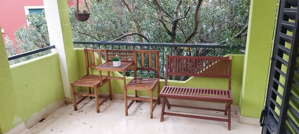 Balcone con panca in legno e sedie tra rami di ulivo