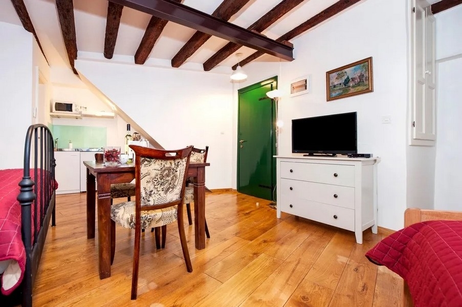 Monolocale con pavimento in legno, TV e angolo cottura aperto