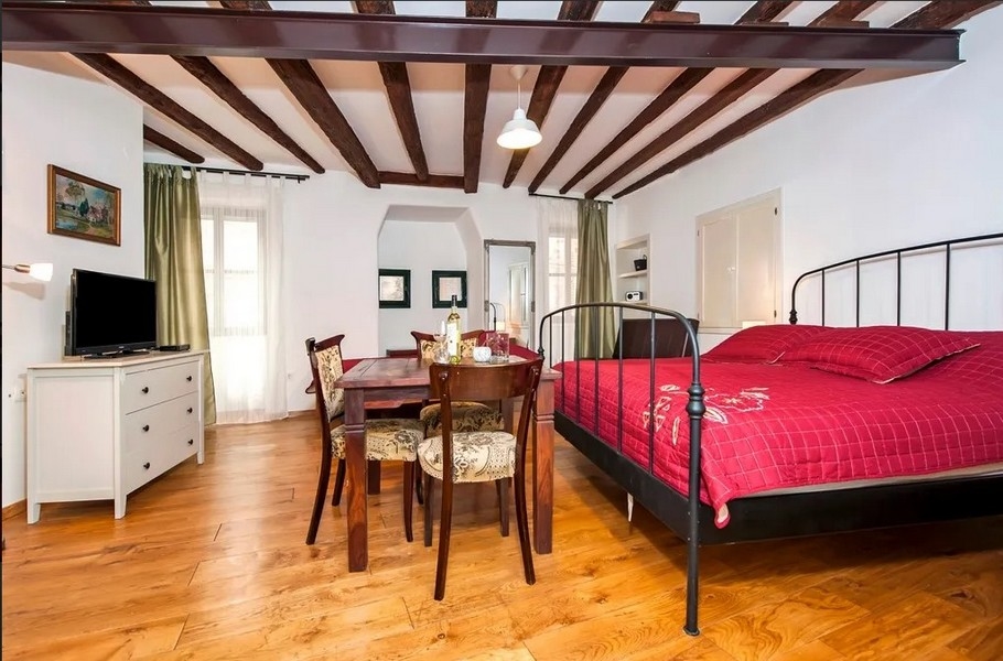 Appartamento luminoso con letto, travi in legno e tavolo