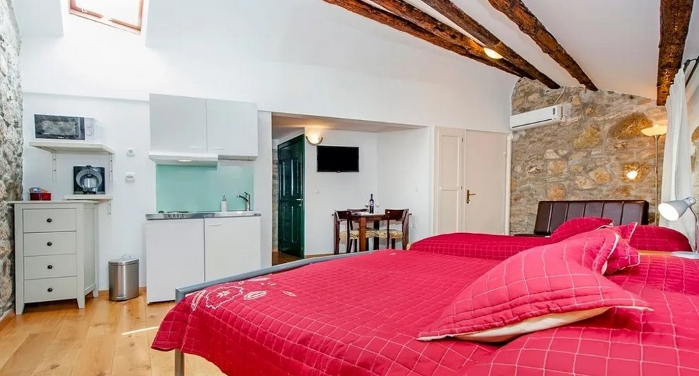 Monolocale con parete in pietra, letto matrimoniale e blocco cucina
