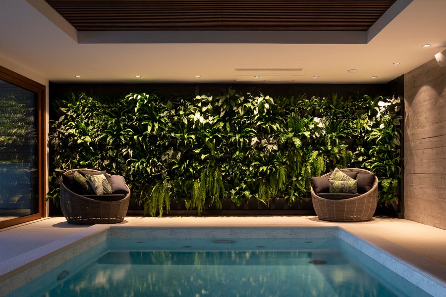 Piscina interna con parete verde di piante e zona seduta