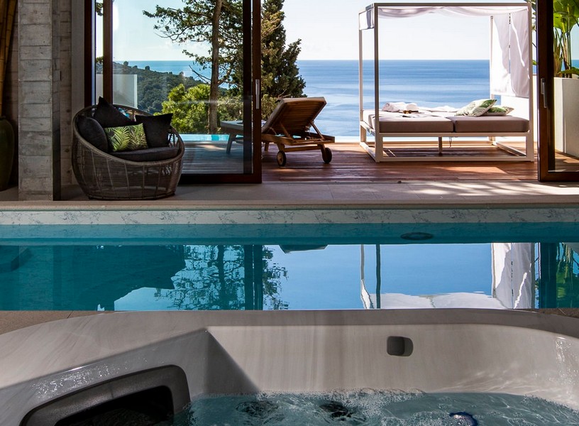Piscina interna con vasca idromassaggio e vista sul solarium con vista mare