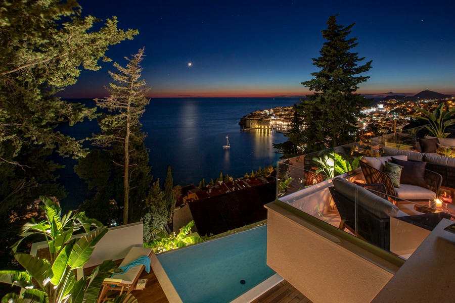Ripresa notturna con piscina e vista sulla città vecchia illuminata di Dubrovnik.