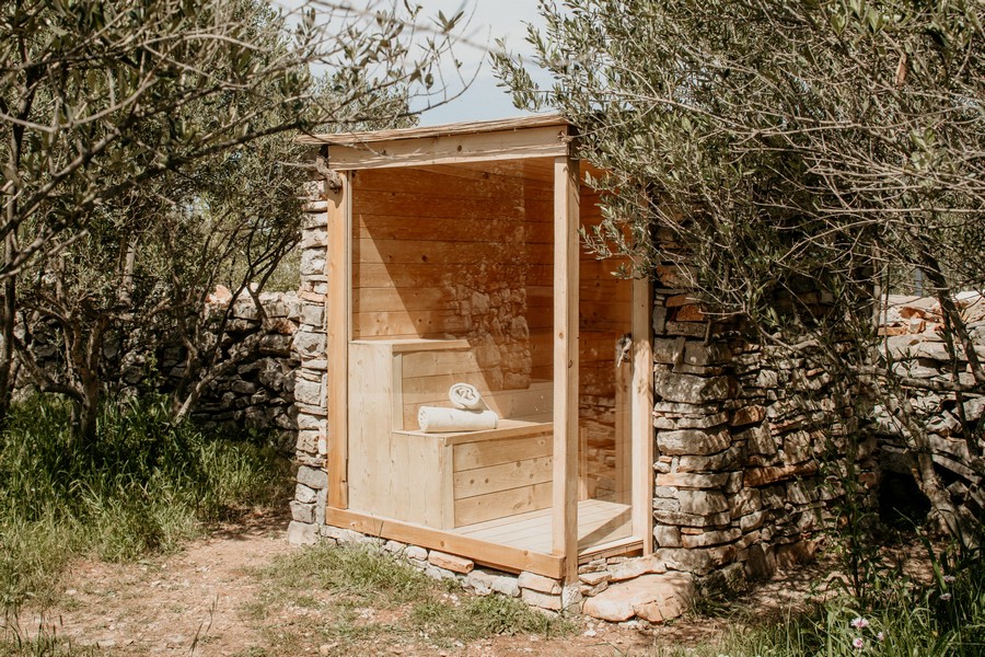 Sauna esterna in giardino con pietra naturale e rivestimento in legno