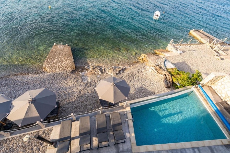 Vista dall'alto su piscina, ombrelloni e pontile per il bagno