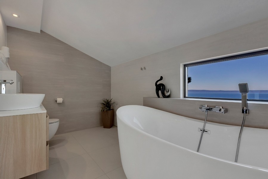 Bagno moderno con vasca freestanding e vista mare