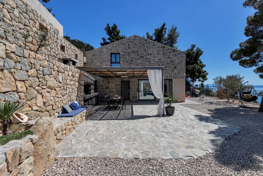 Casa in pietra con tende alla pergola e cortile pavimentato