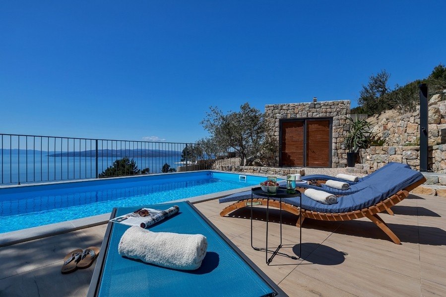 Piscina con sedie a sdraio e vista mare