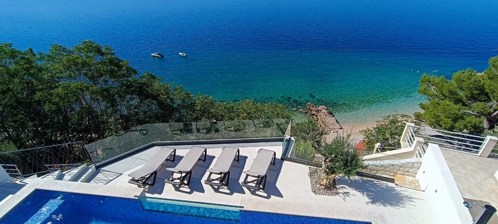 Casa bifamiliare sopra la spiaggia di ghiaia con piscina e lettini