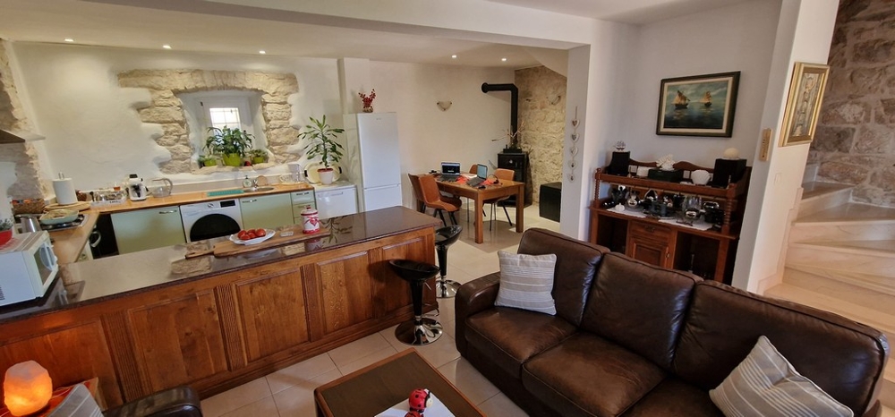 Soggiorno con cucina, zona pranzo e parete in pietra naturale
